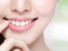 A closeup of a young women with bright smile showing her white teeth , placed her finger near her lips.